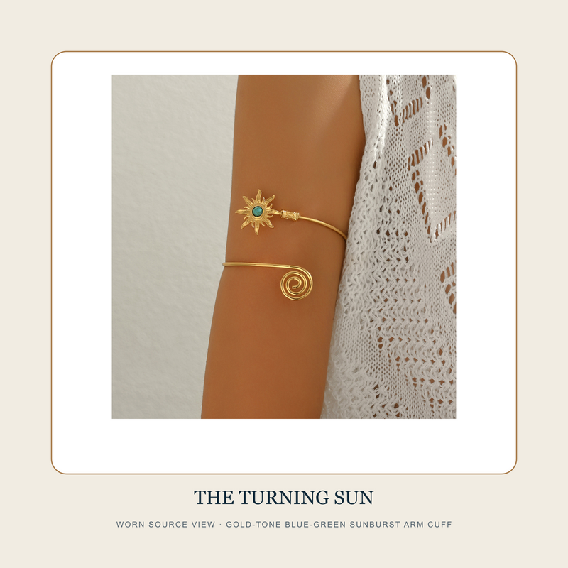 Worn source view of The Turning Sun gold-tone upper-arm cuff with blue-green sunburst center and spiral terminal