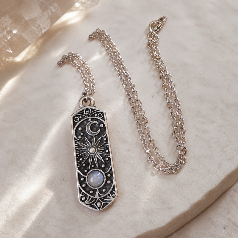 The Three Lights celestial necklace arranged on pale ivory stone