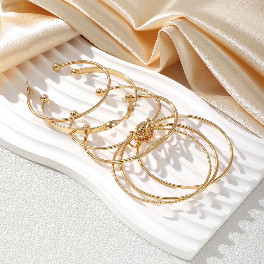 Source flat lay of the six gold-tone bangles included in The Six Kept Lines set