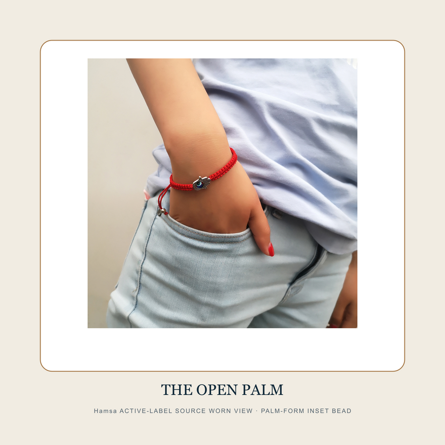 Worn source view of The Five Red Knots palm-form inset-bead red-cord bracelet