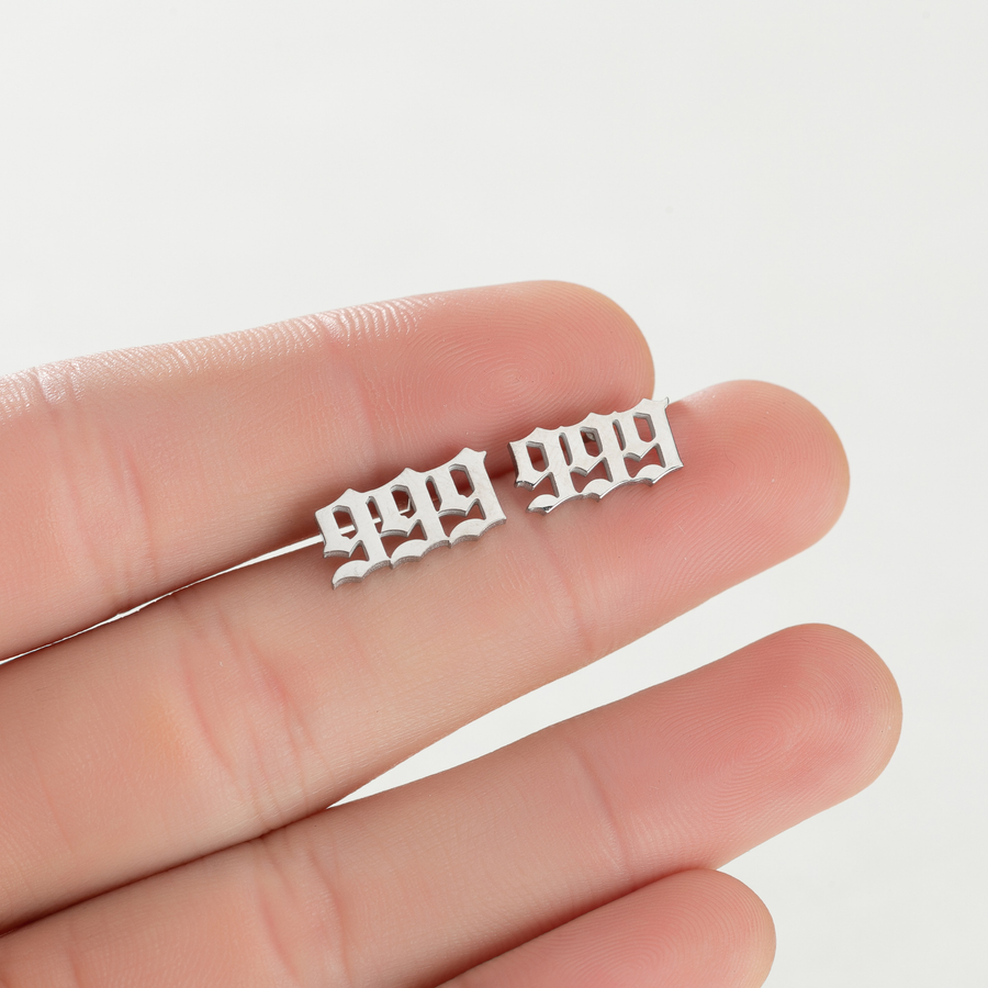 Steel-tone 999 Whispered Number stud earrings shown on fingers for visual scale