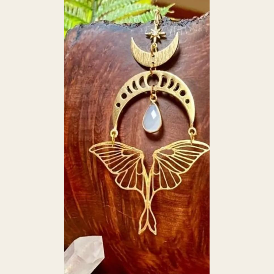 Single-earring detail showing The Moonmoth star, crescent, pale teardrop and openwork moth-style drop