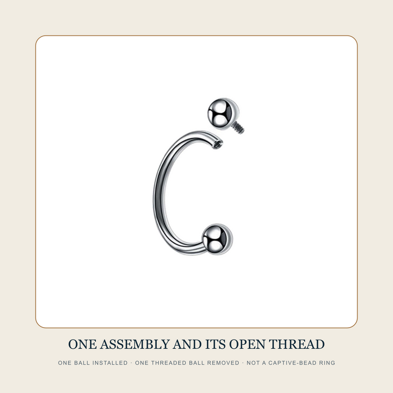 Steel-tone circular barbell source witness with one threaded ball installed and one removed beside the open internally threaded body