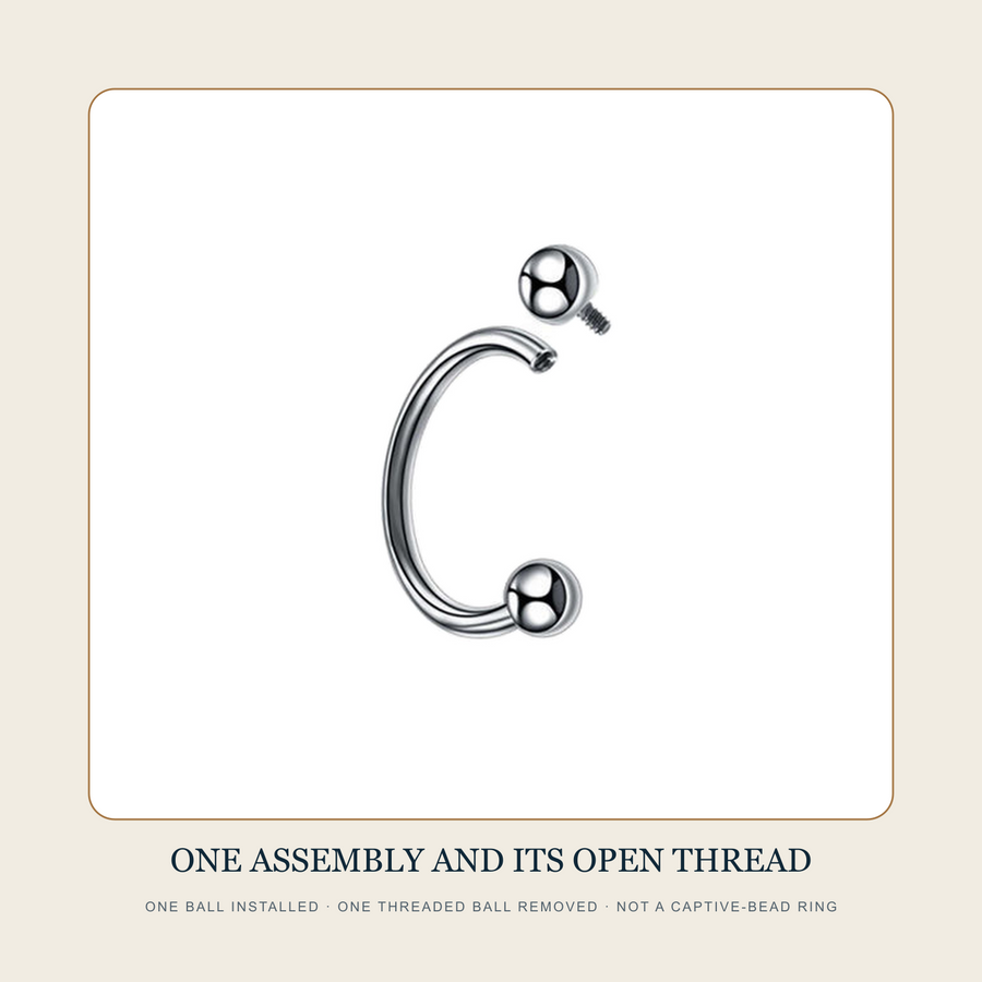 Steel-tone circular barbell source witness with one threaded ball installed and one removed beside the open internally threaded body