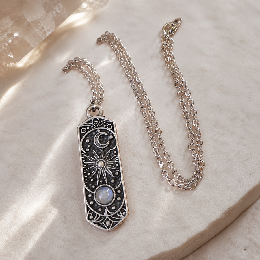 The Three Lights celestial necklace arranged on pale ivory stone