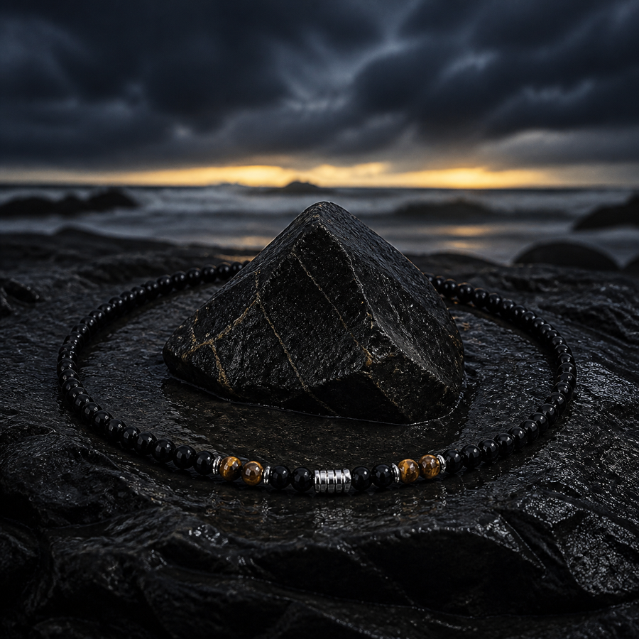 The Anchor Stone necklace encircling a dark stone on a stormy shoreline