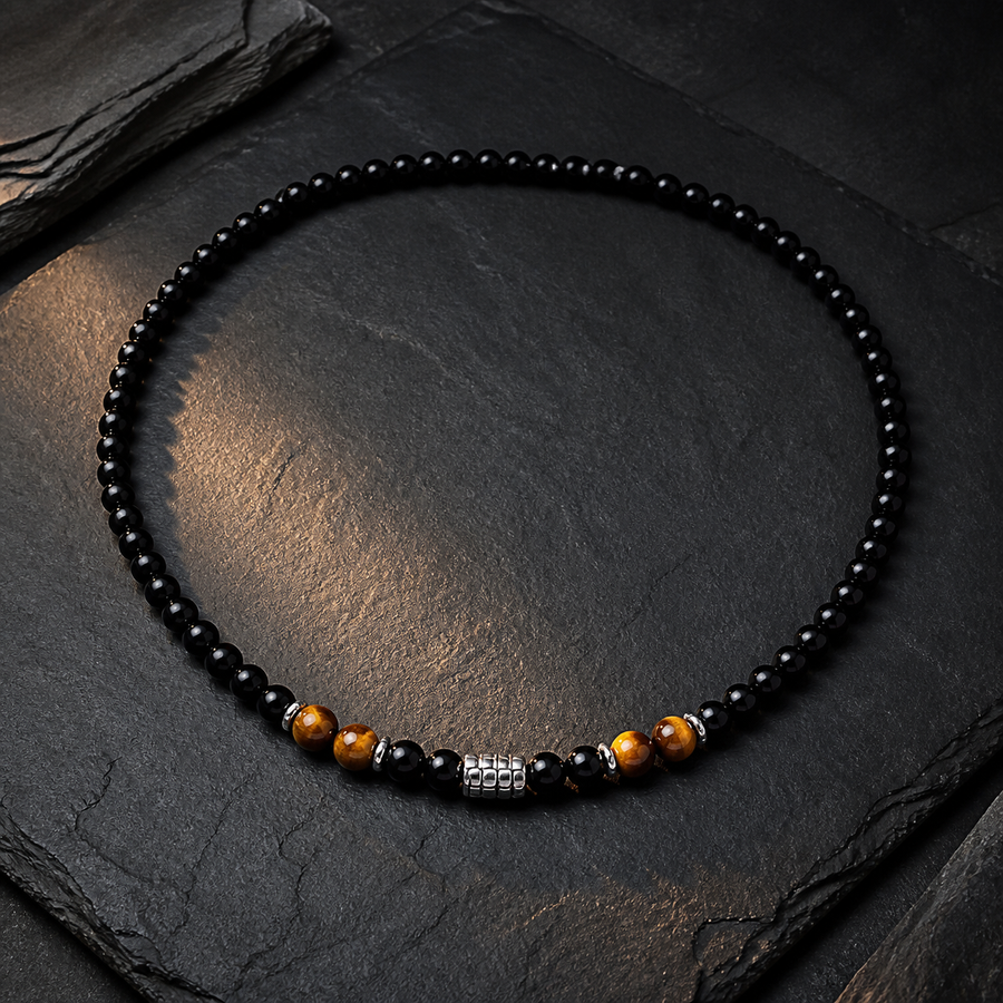 The Anchor Stone black and golden-brown bead necklace arranged on slate